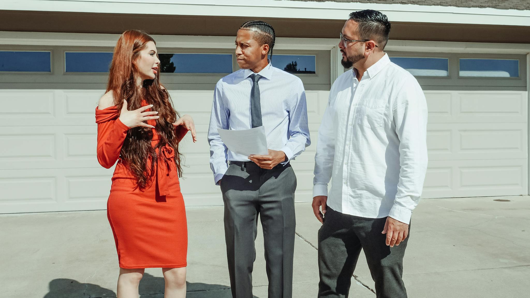 A young couple talking to a real estate agent outside a modern home.